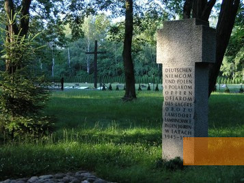 Bild:Lamsdorf, 2005, Granitdenkmal für die Opfer des Arbeitslagers Lamsdorf, im Hintergrund der Friedhof für die Opfer,  Centralne Muzeum Jeńców Wojennych w Łambinowicach-Opolu