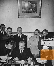 Bild:Moskau, 23. August 1939, Außenminister Molotow unterschreibt den deutsch-sowjetischen Nichtangriffspakt, im Hintergrund von Ribbentrop und Stalin, public domain