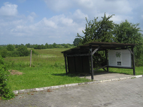 Königsgut, 2010, Informationstafel, dahinter das ehemalige Lagergelände, Stiftung Denkmal