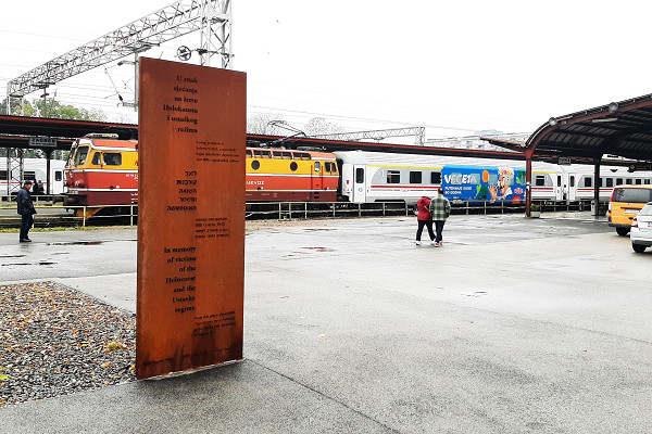 Zagreb, 2023, Gedenktafel des Holocaustdenkmals mit dem Hauptbahnhof im Hintergrund, Stiftung Denkmal