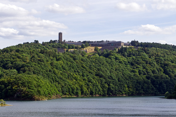 NS-Ordensburg Vogelsang, 2019, Ansicht der ehemaligen NS-Ordensburg Vogelsang vor dem Urftsee, Thomas Römer / Wikimedia Commons